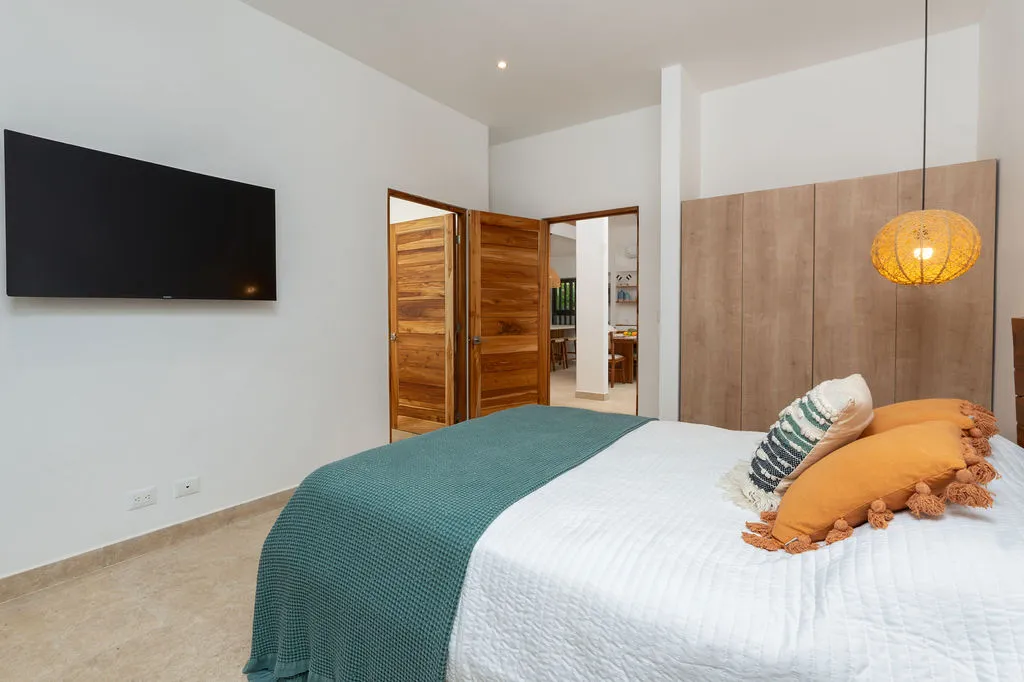 Bedroom with a wall-mounted television and an open door through to the ensuite bathroom